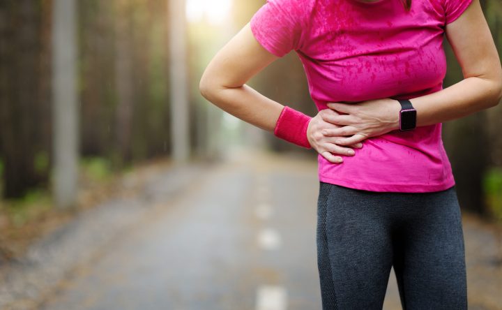 Side stitch - woman runner side cramps. Marathon.