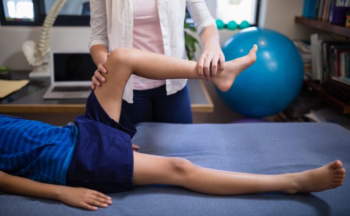 Low section of boy being examined by female therapist at hospital ward